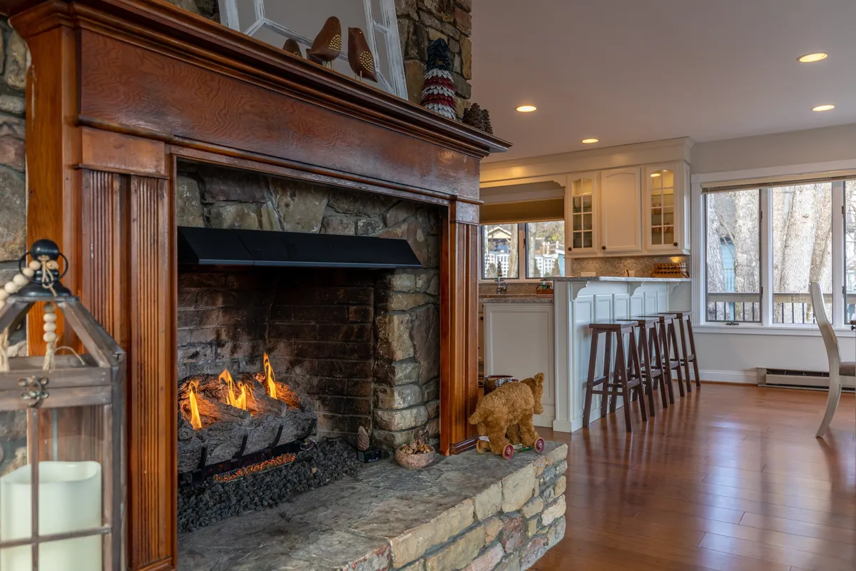 This image showcases a spacious interior featuring a welcoming fireplace, a large kitchen island, and expansive windows that fill the space with light. The open-concept design visually connects the kitchen and living areas, while the windows frame stunning mountain views beyond.
